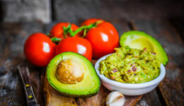 Guacamaole with bread and avocado on rustic wooden background