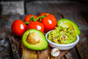 Guacamaole with bread and avocado on rustic wooden background