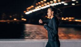 Young middle east woman jogging at night looking in fitness tracker on her wrist